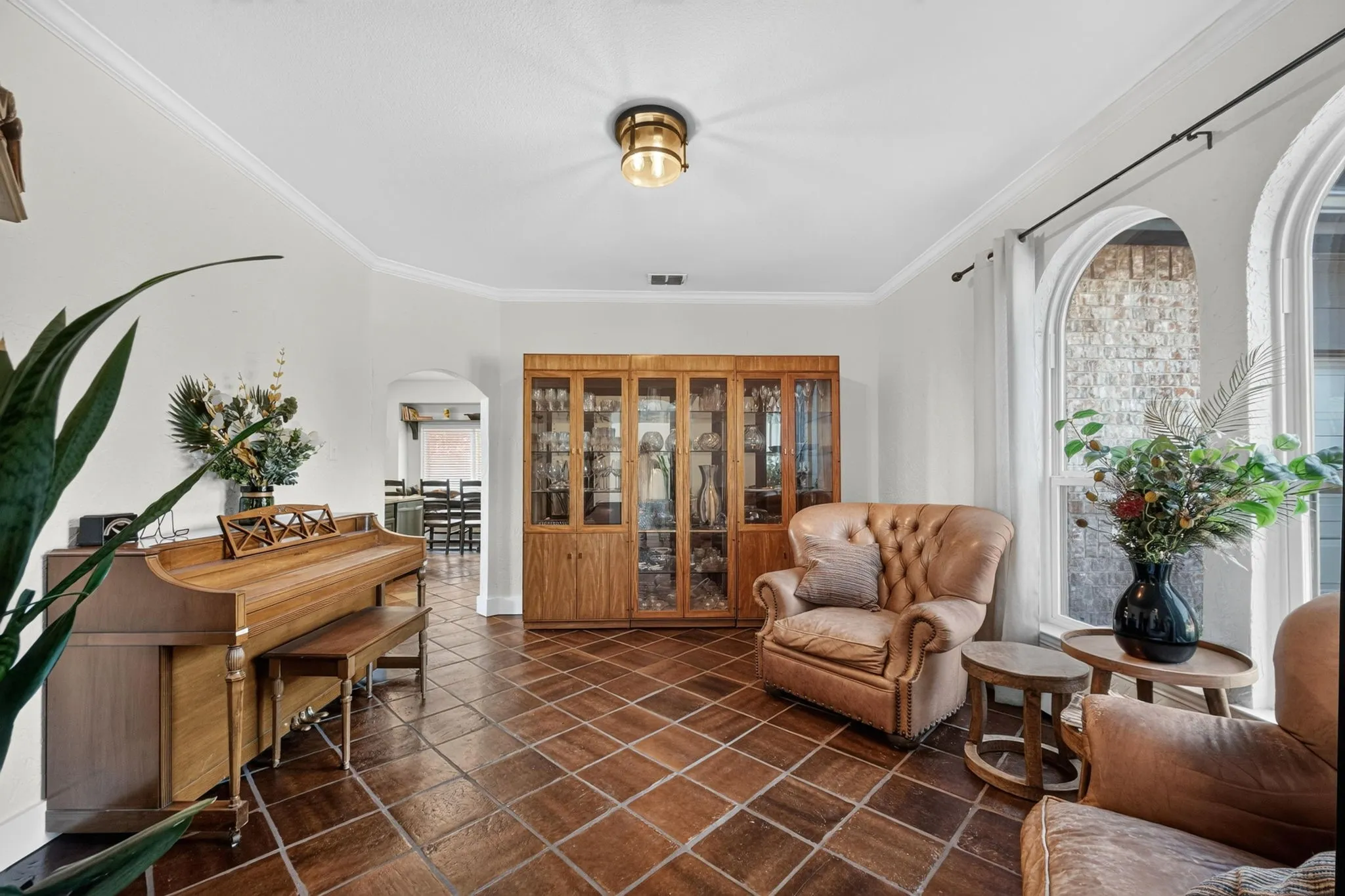 Arched windows, beautiful flooring, crown molding, built-in display cabinetry, and a brass-tone flush-mount light fixture