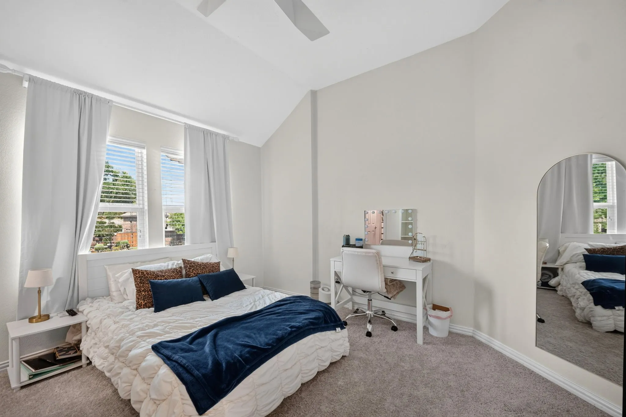 Vaulted ceiling, ceiling fan, carpet flooring, and multiple windows.