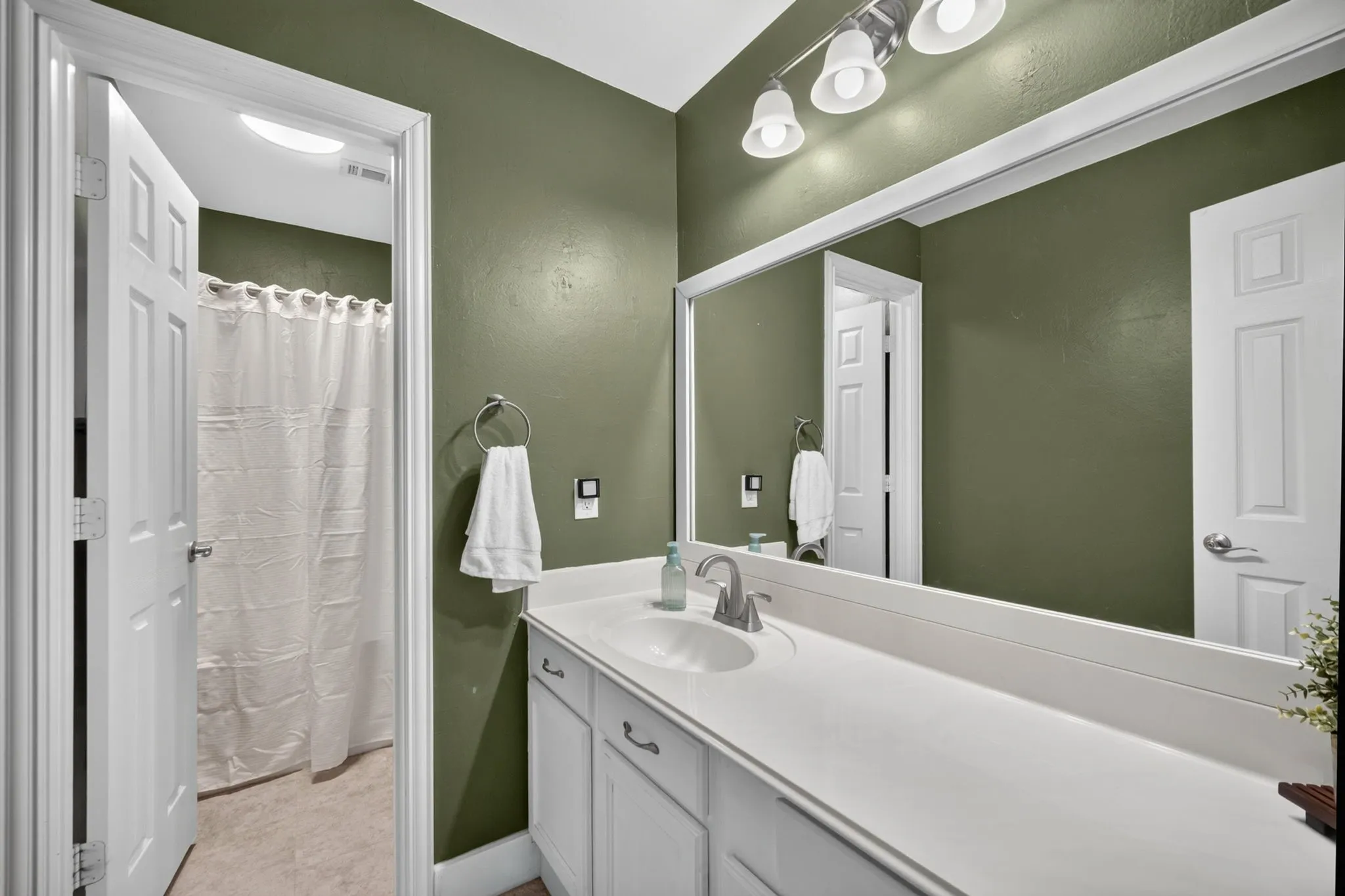 Bathroom featuring a single vanity with an integrated sink, white cabinetry, and a full-width mirror