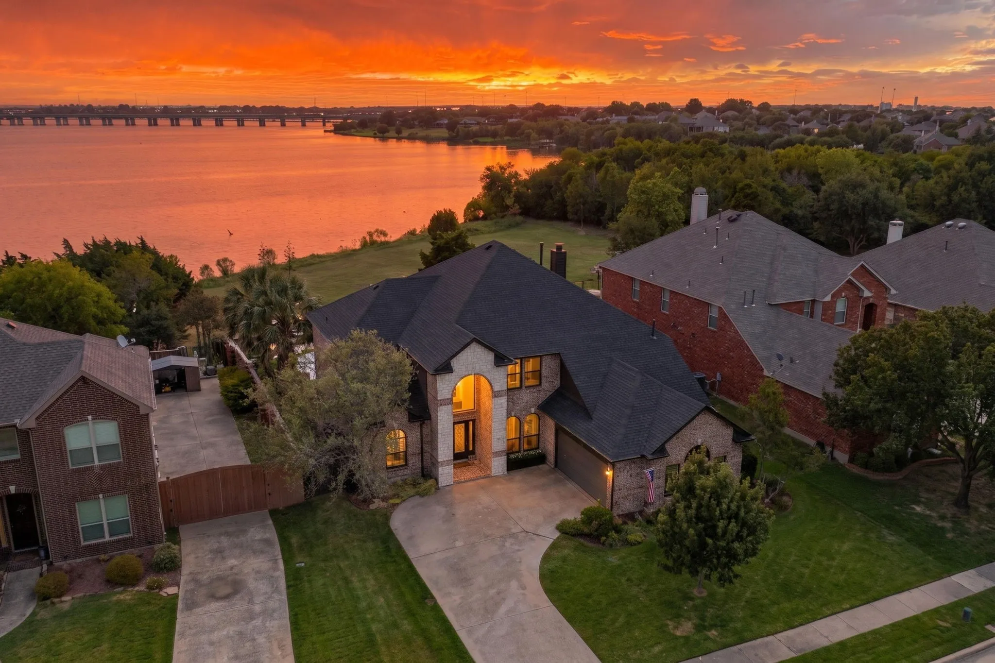 Stately residence featuring a brick and stone exterior, arched entryway, attached garage, and mature landscaping