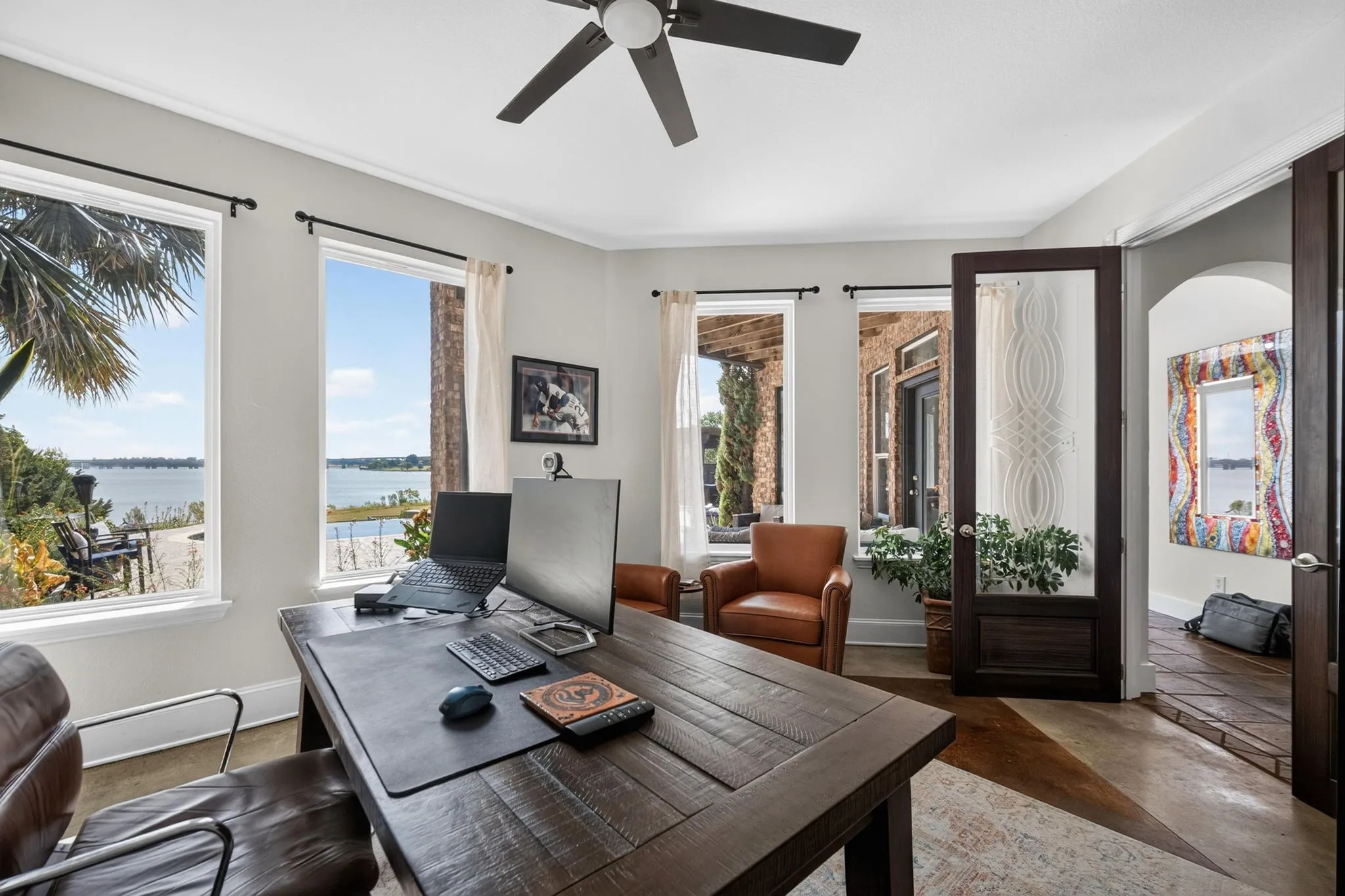 Room featuring multiple windows, a ceiling fan and a dark wood-finish paneled door with glass insert