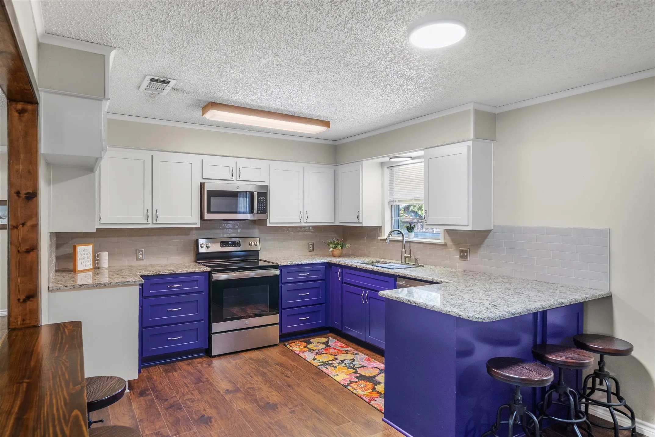 Granite countertops, breakfast bar and violet painted cabinets make this an uplifting kitchen