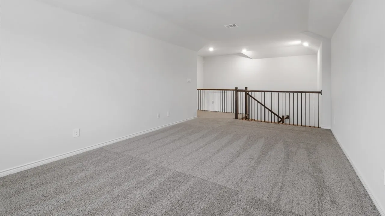 Loft area featuring grey carpeting and a dark metal railing