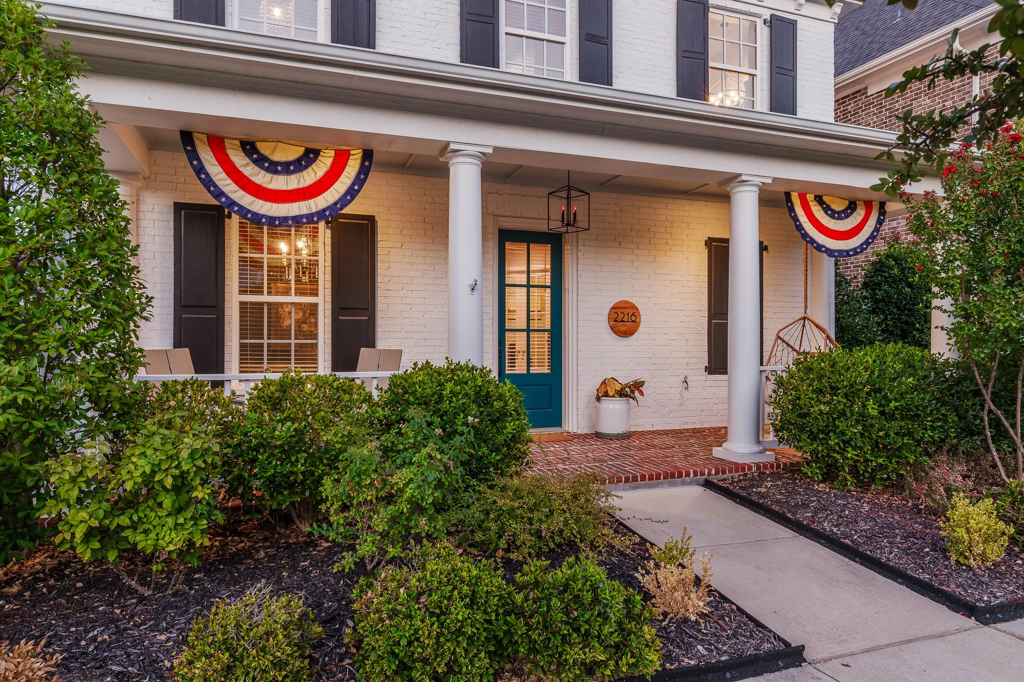 White brick facade with black louvered shutters offer a gorgeous walk up curb appeal