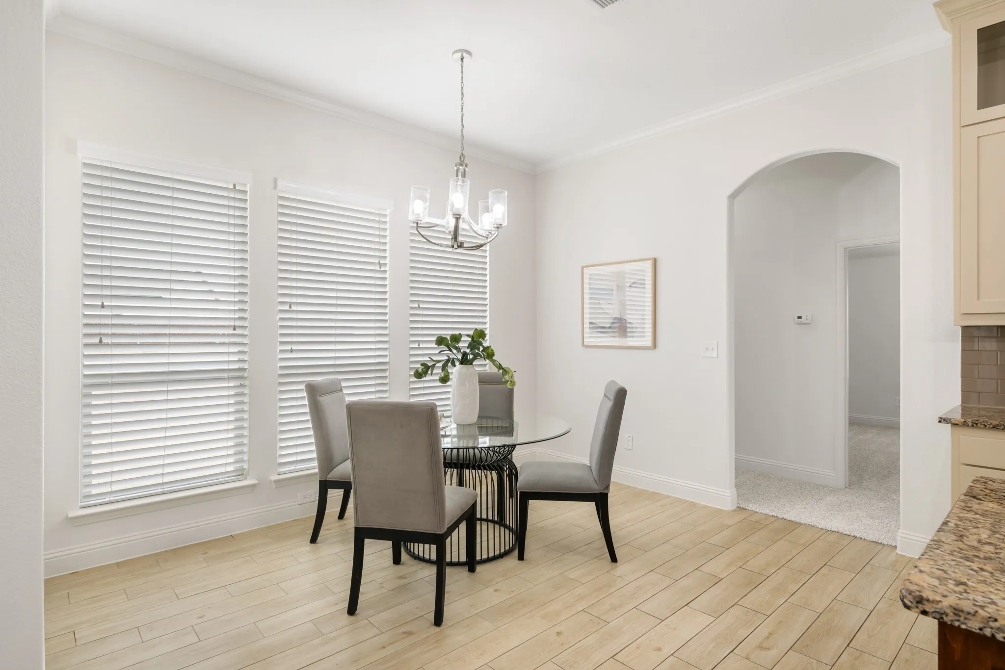 Wood-finish flooring, multiple windows with blinds, arched entryway, and crown molding