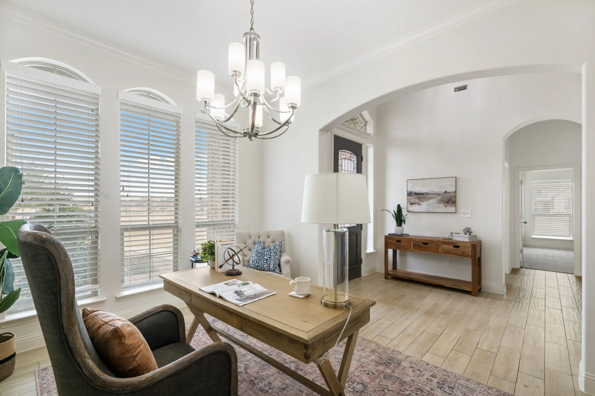 Large arched windows with blinds, wood-finish flooring, recessed lighting, and an arched entry