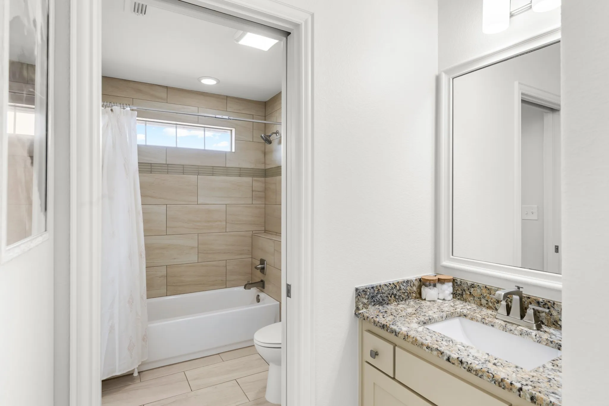 Master bathroom featuring dual vanity with speckled quartz countertop, polished chrome fixtures, and large framed mirror