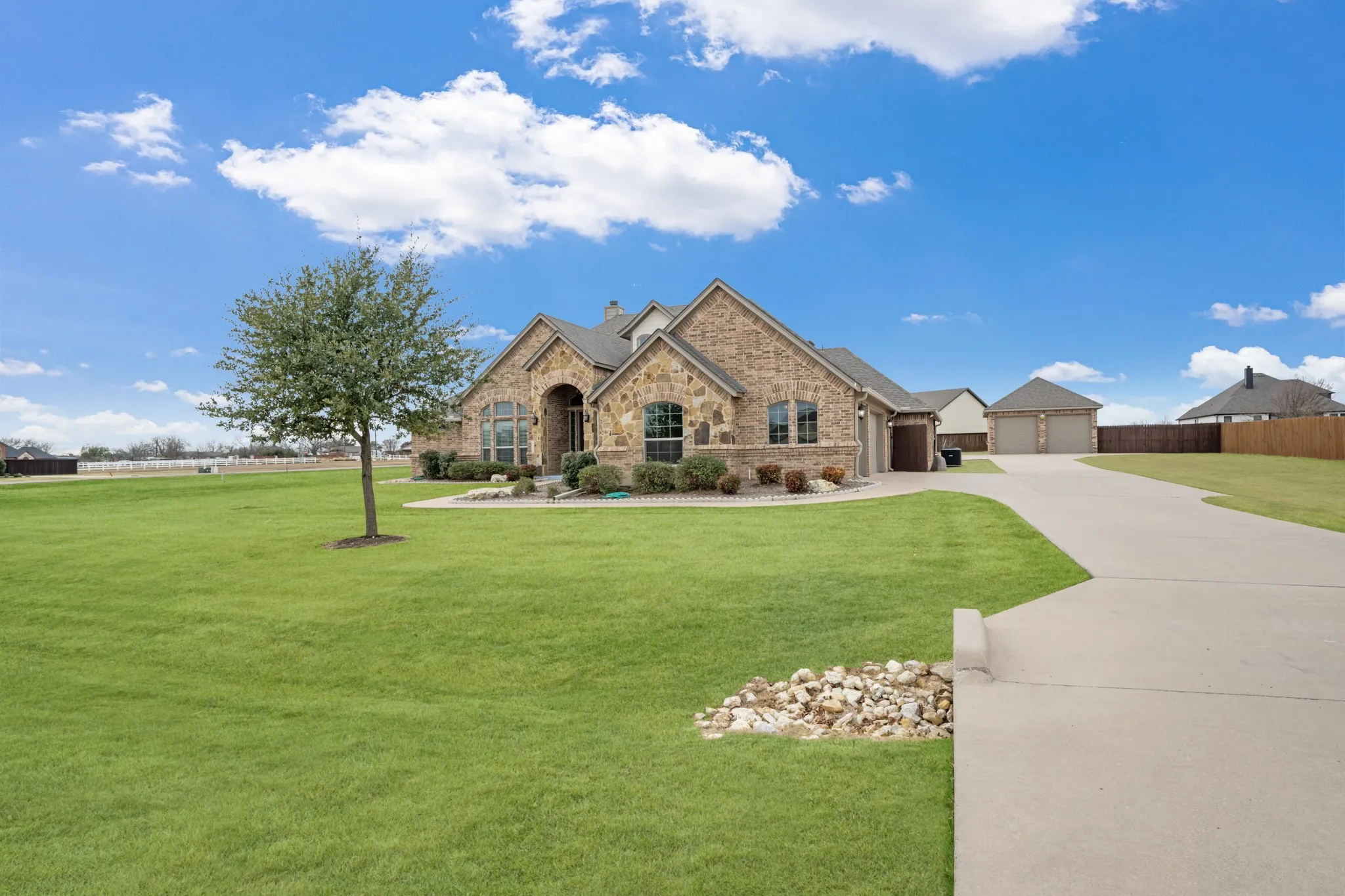 Stone and brick exterior residence with an arched entry, a concrete driveway, and an attached garage