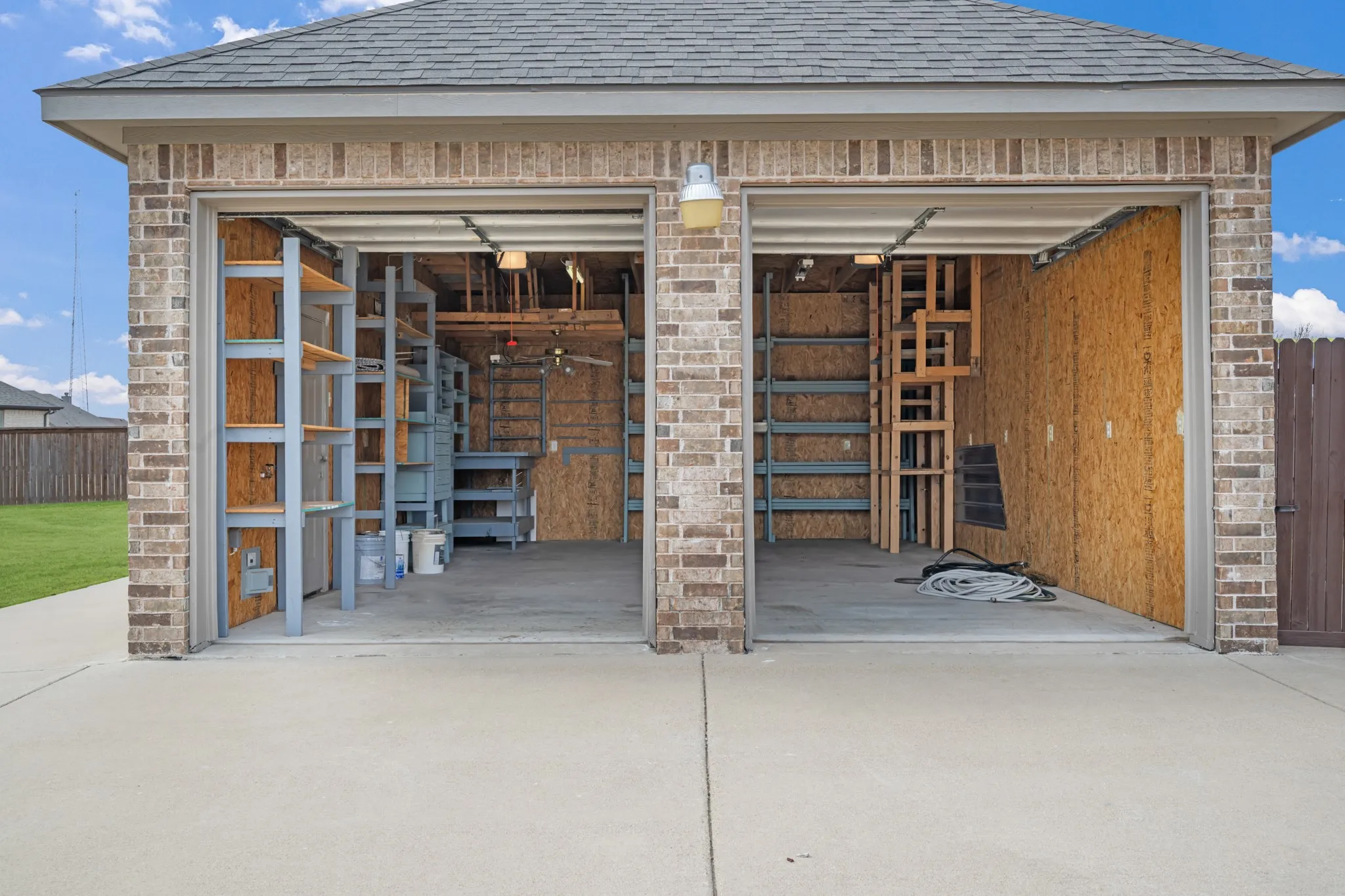 Two-bay garage with brick exterior, concrete driveway, and built-in shelving