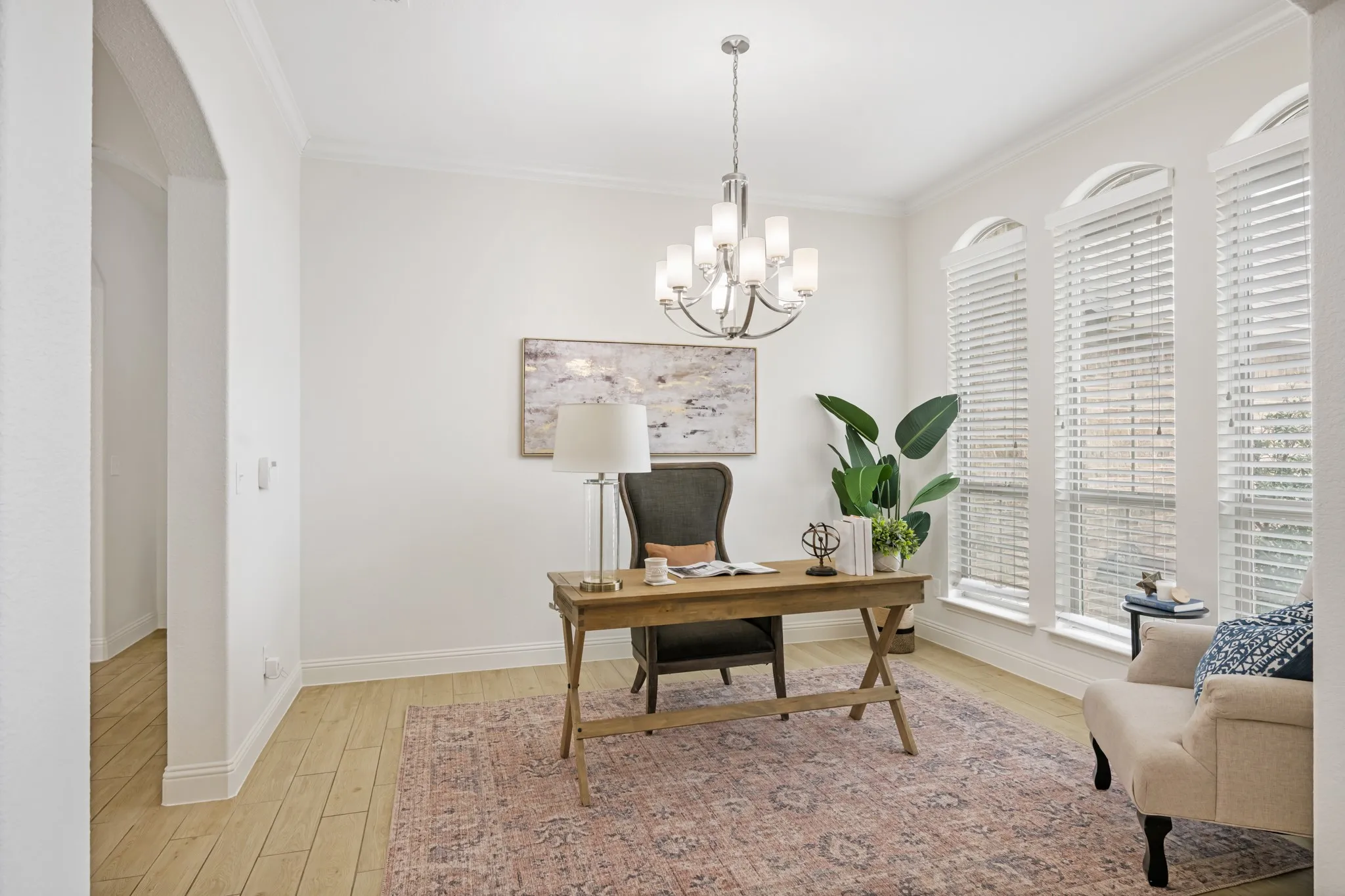 Arched entryway with crown molding, wood-finish flooring, a contemporary chandelier, and multiple arched windows