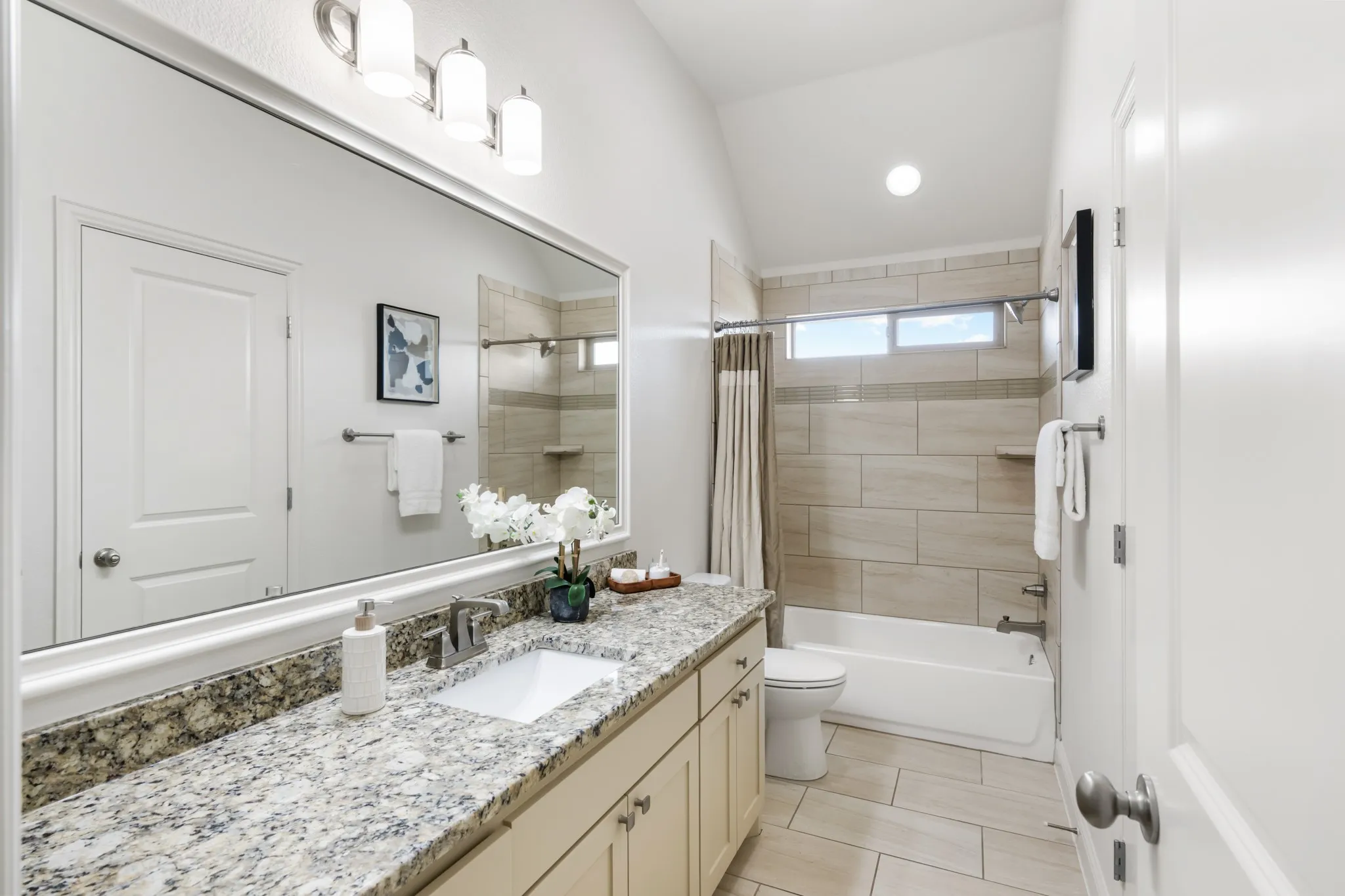 Spa-inspired bathroom featuring a granite countertop vanity with dual sinks, polished nickel fixtures, and ample storage