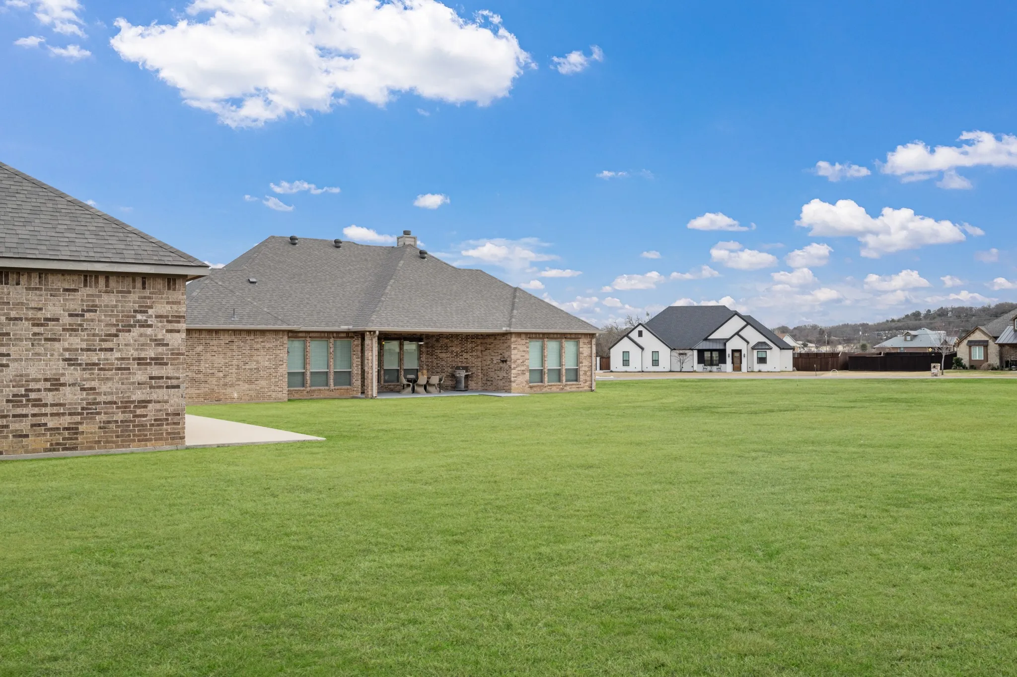 Expansive manicured lawn with lush green grounds showcasing the brick exterior and multi-gabled roofline of this residential estate