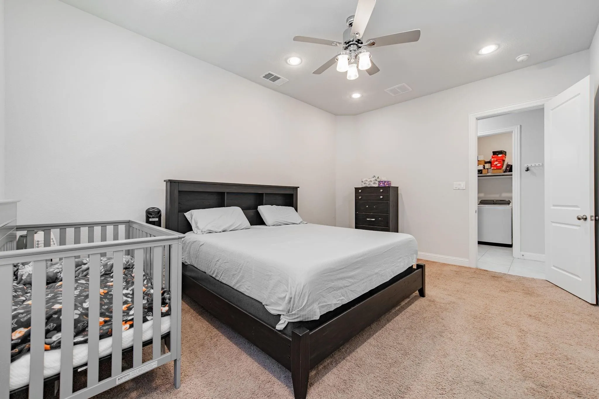 Spacious primary bedroom with dark wood platform bed frame, neutral wall finishes, and carpeted flooring