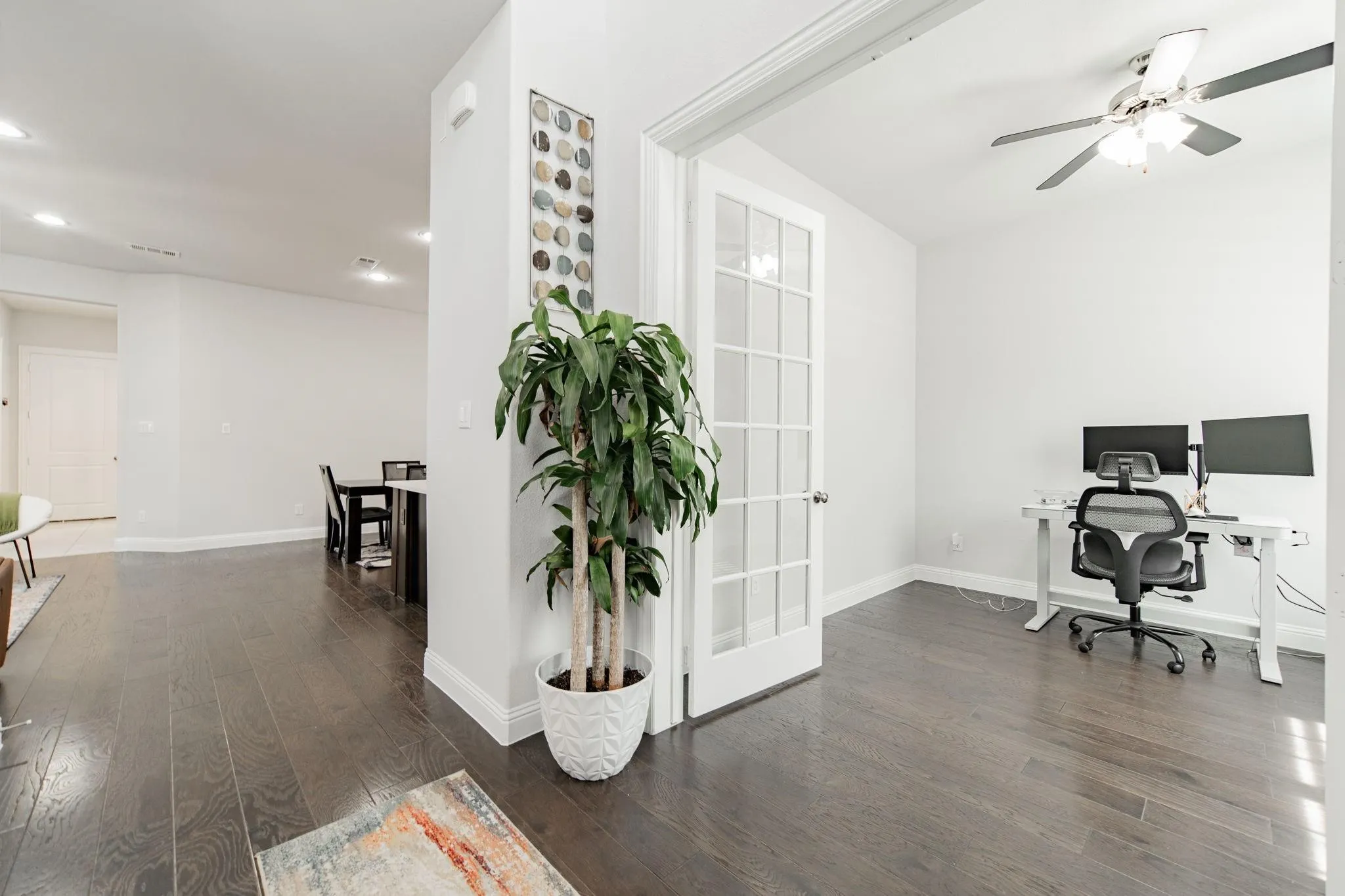 Dark wood-finish flooring throughout, French doors with glass panels, recessed lighting, and ceiling fan with light fixture