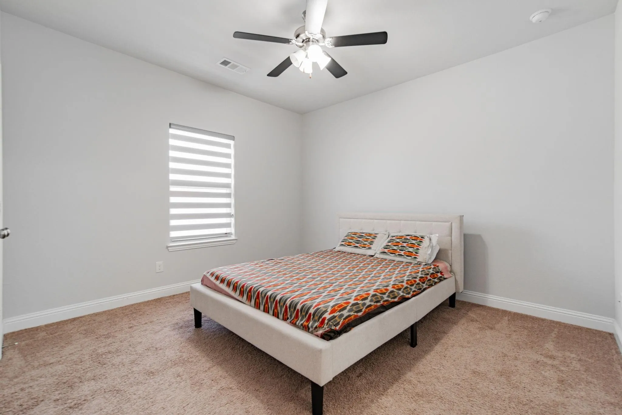 Neutral wall paint, plush carpet flooring, window with blinds, ceiling fan, and white trim