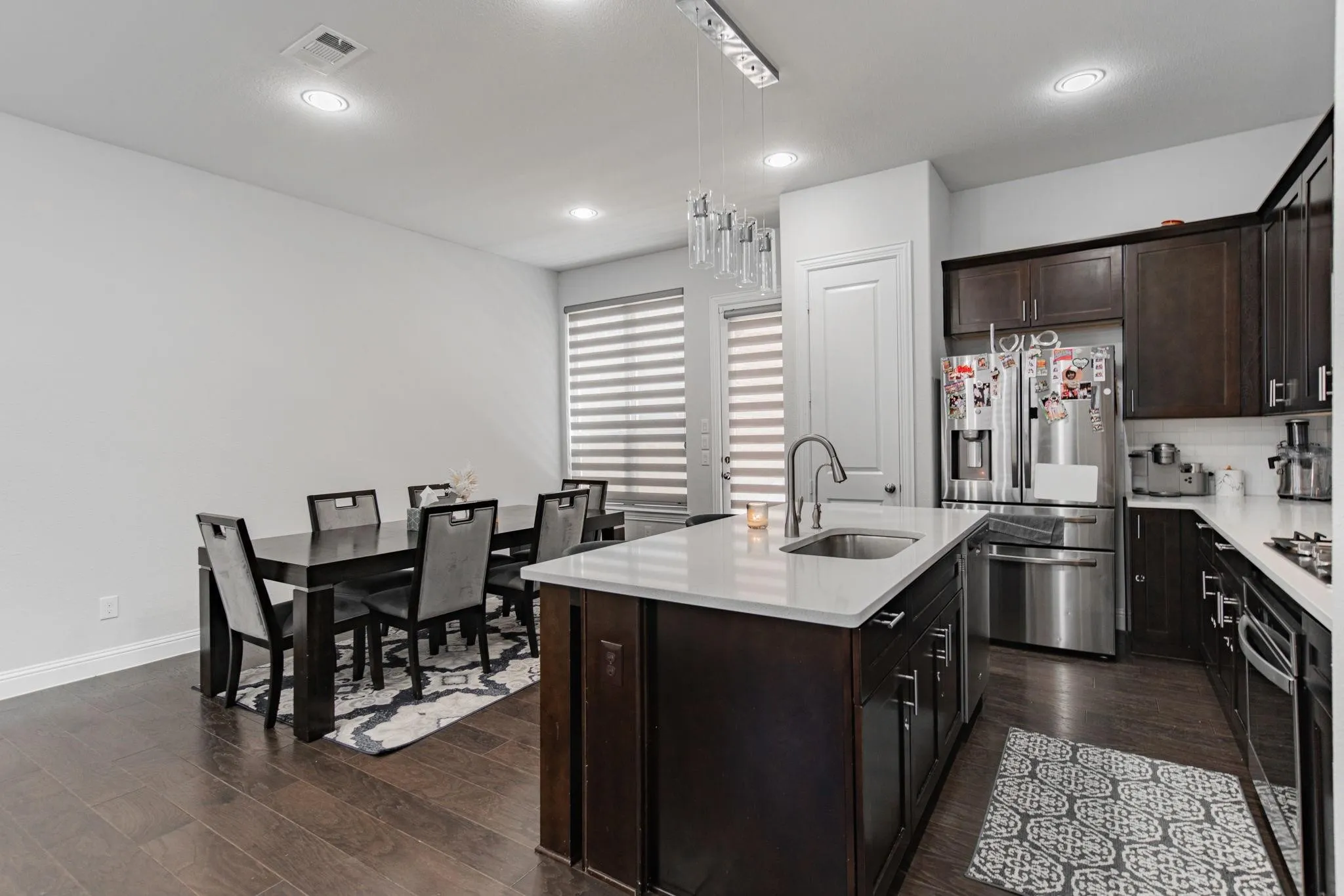 Kitchen with dark wood-finish flooring, recessed lighting, and a kitchen island with a single-basin sink