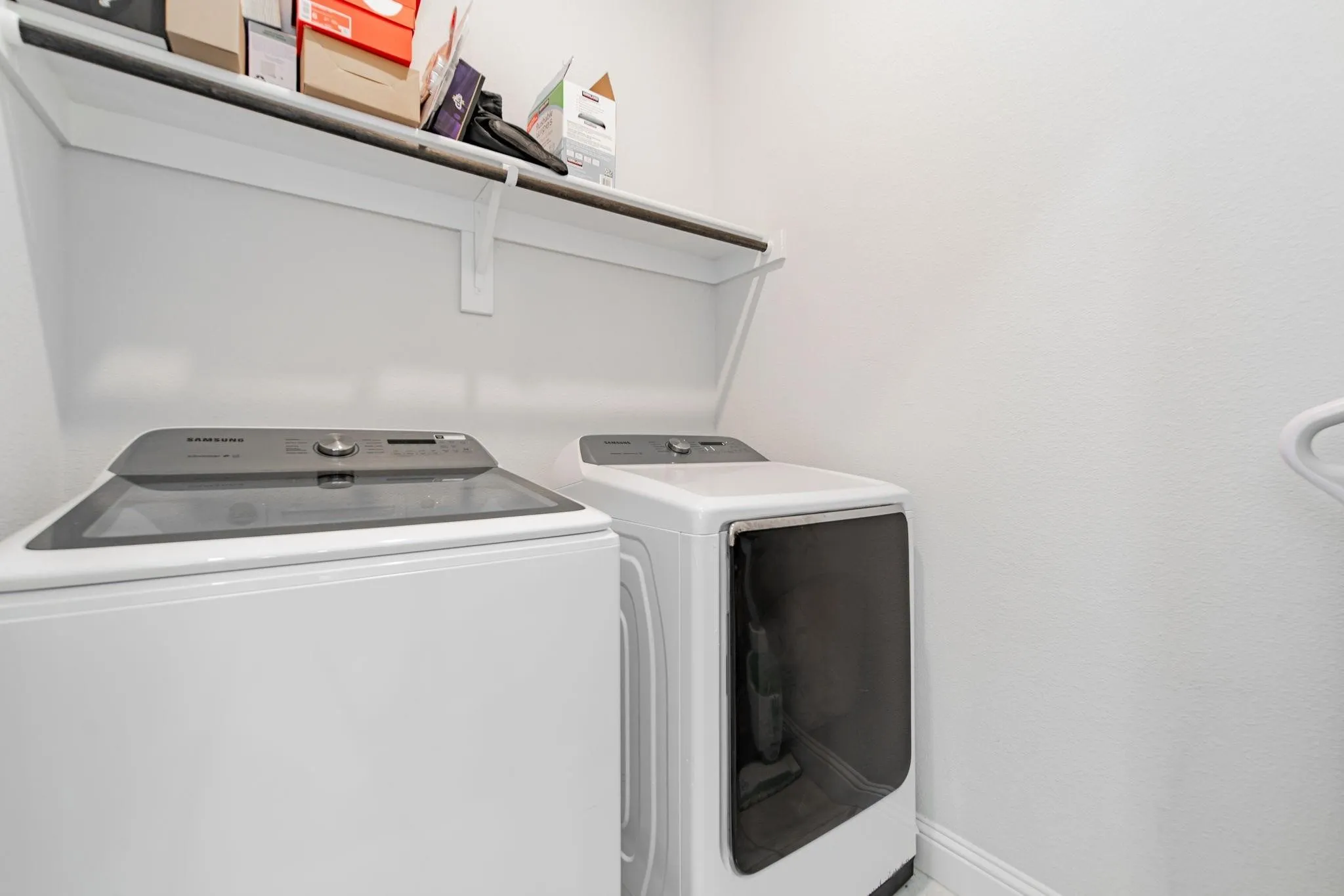 Laundry area featuring a built-in shelf and integrated hanging rod