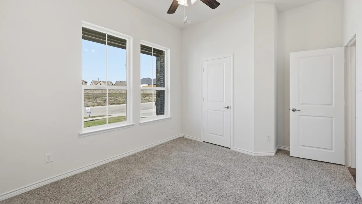 Neutral tone wall paint, light gray carpeting, two panel interior doors, and a ceiling fan with integrated lighting