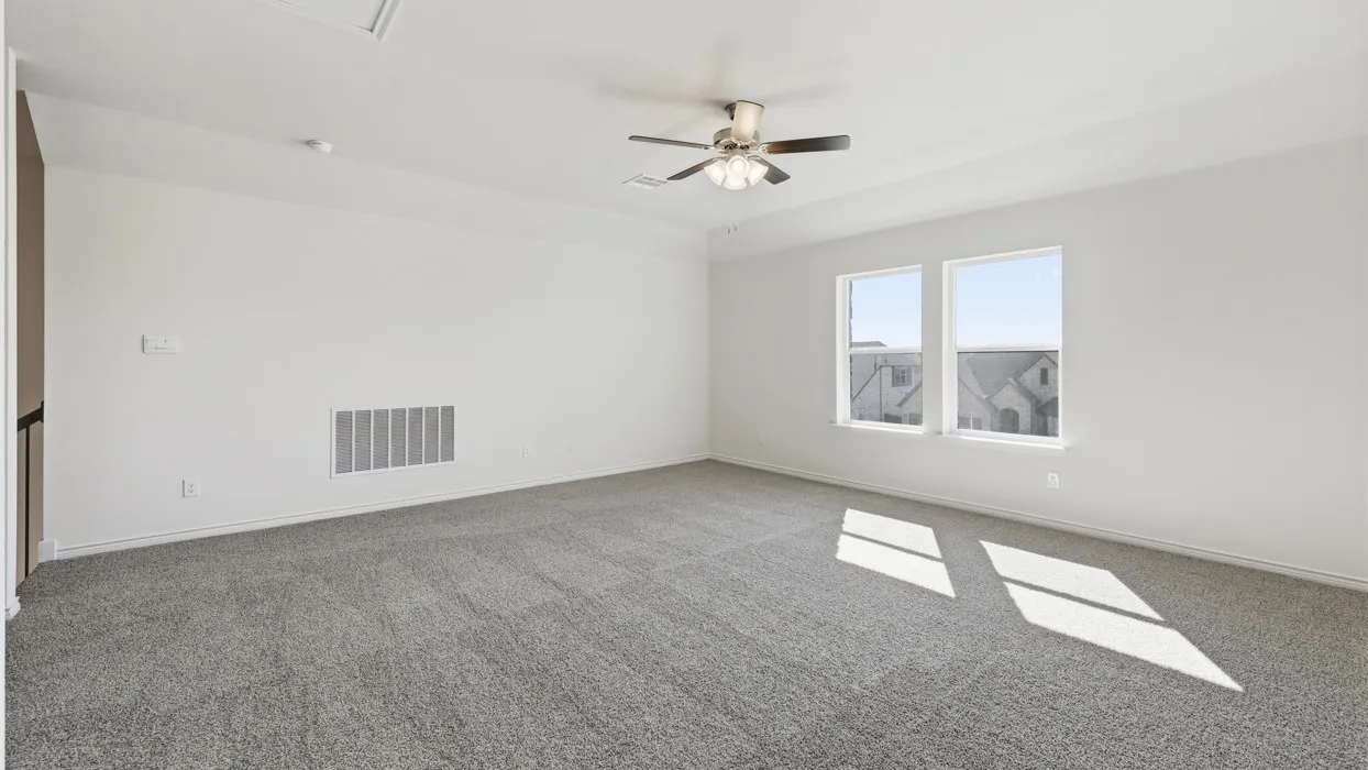 Spacious room featuring neutral carpeting, two windows, and a ceiling fan with integrated lighting