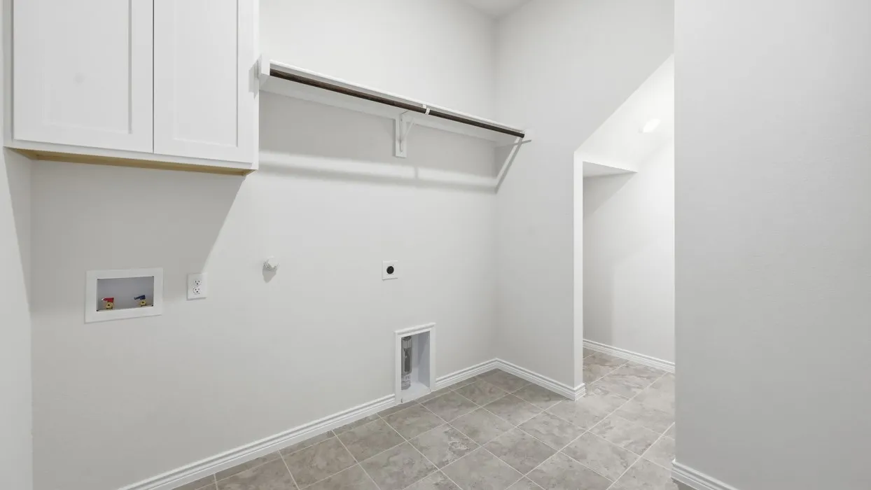 Bright, open laundry room featuring white cabinetry, tile flooring, and abundant natural light from transom window