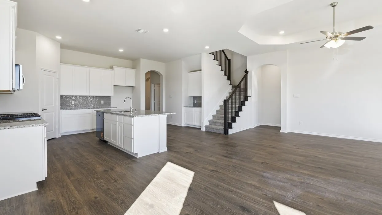 Open-concept living and kitchen area featuring white cabinetry, stainless steel appliances, dark wood-finish flooring, recessed and ceiling fan lighting, and a floating kitchen island