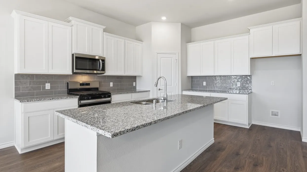 Kitchen featuring a central island with a sink, white cabinetry, stainless steel microwave, gas range, and wood-finish flooring