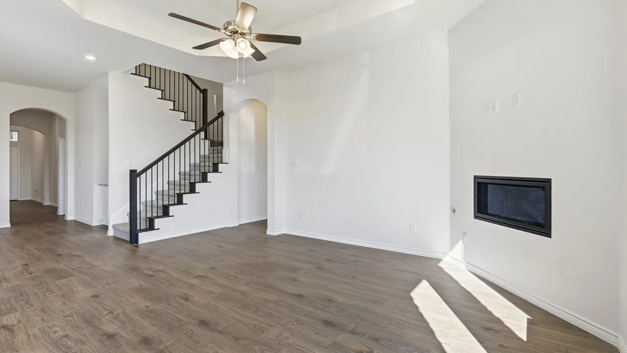 Spacious interior with wood-finish flooring, a built-in fireplace, and a staircase with wrought iron balusters