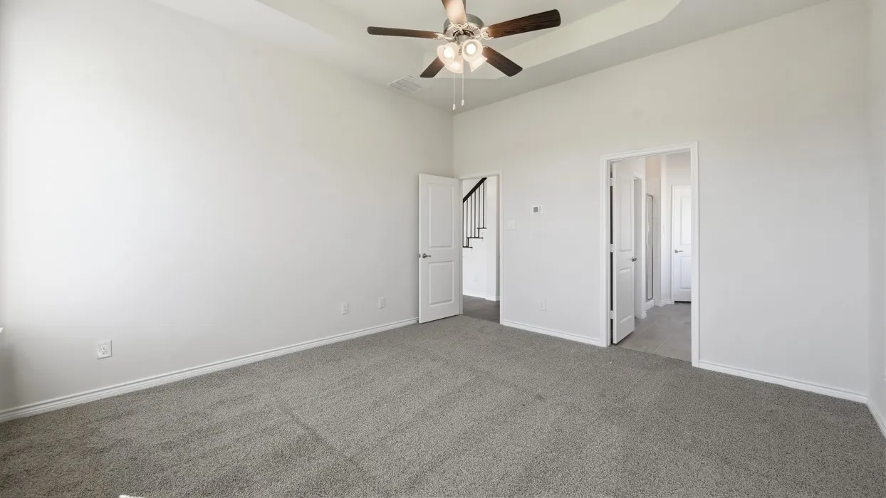 Tray ceiling with a ceiling fan, light gray carpeting, and white painted walls