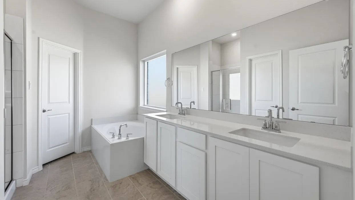Spa-inspired primary bathroom featuring dual vanities with quartz countertops, an undermount sink, polished chrome fixtures, and an expansive framed mirror