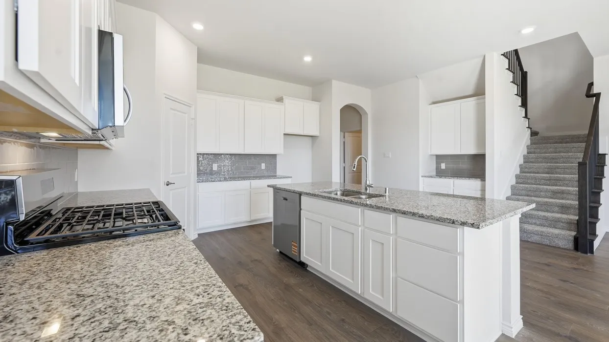 Chef's kitchen featuring white shaker cabinetry, stainless steel appliances including a gas cooktop, granite countertops, a large center island with seating, subway tile backsplash, and wood-finish flooring throughout the open-concept space