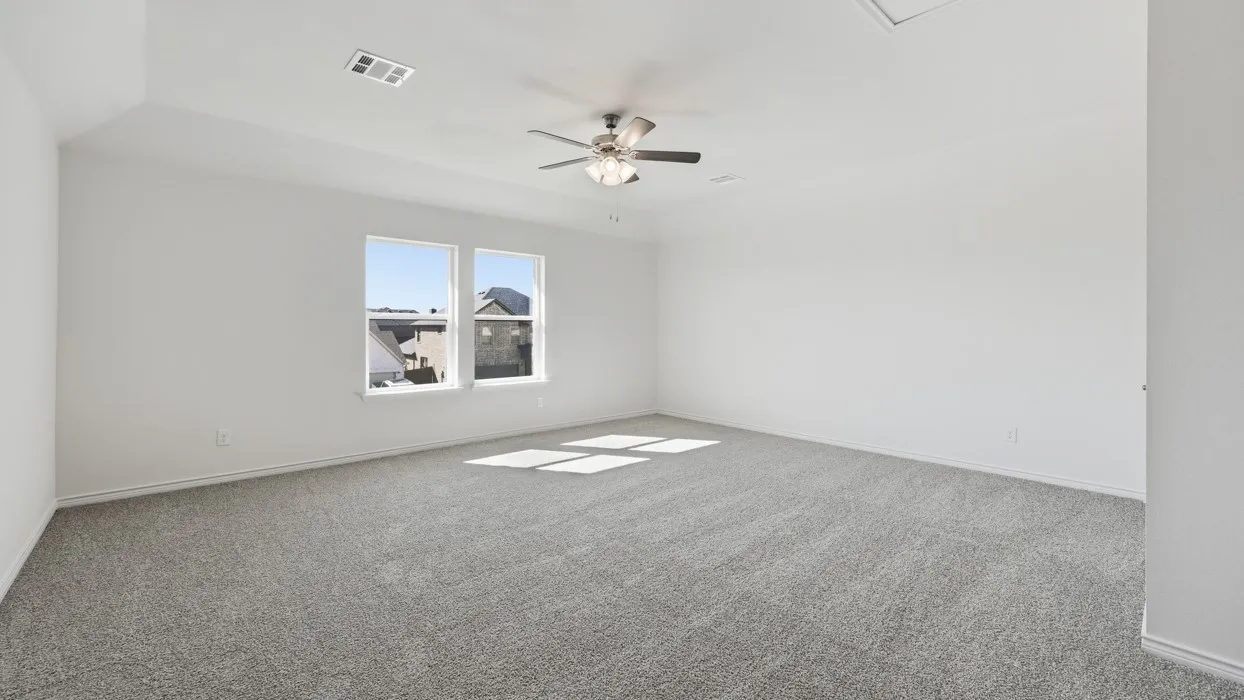 Spacious room featuring gray carpet flooring, dual windows, and a ceiling fan with integrated​​‌​​​​‌​​‌‌​‌‌​​​‌‌​‌​‌​‌​​​‌​​ lighting