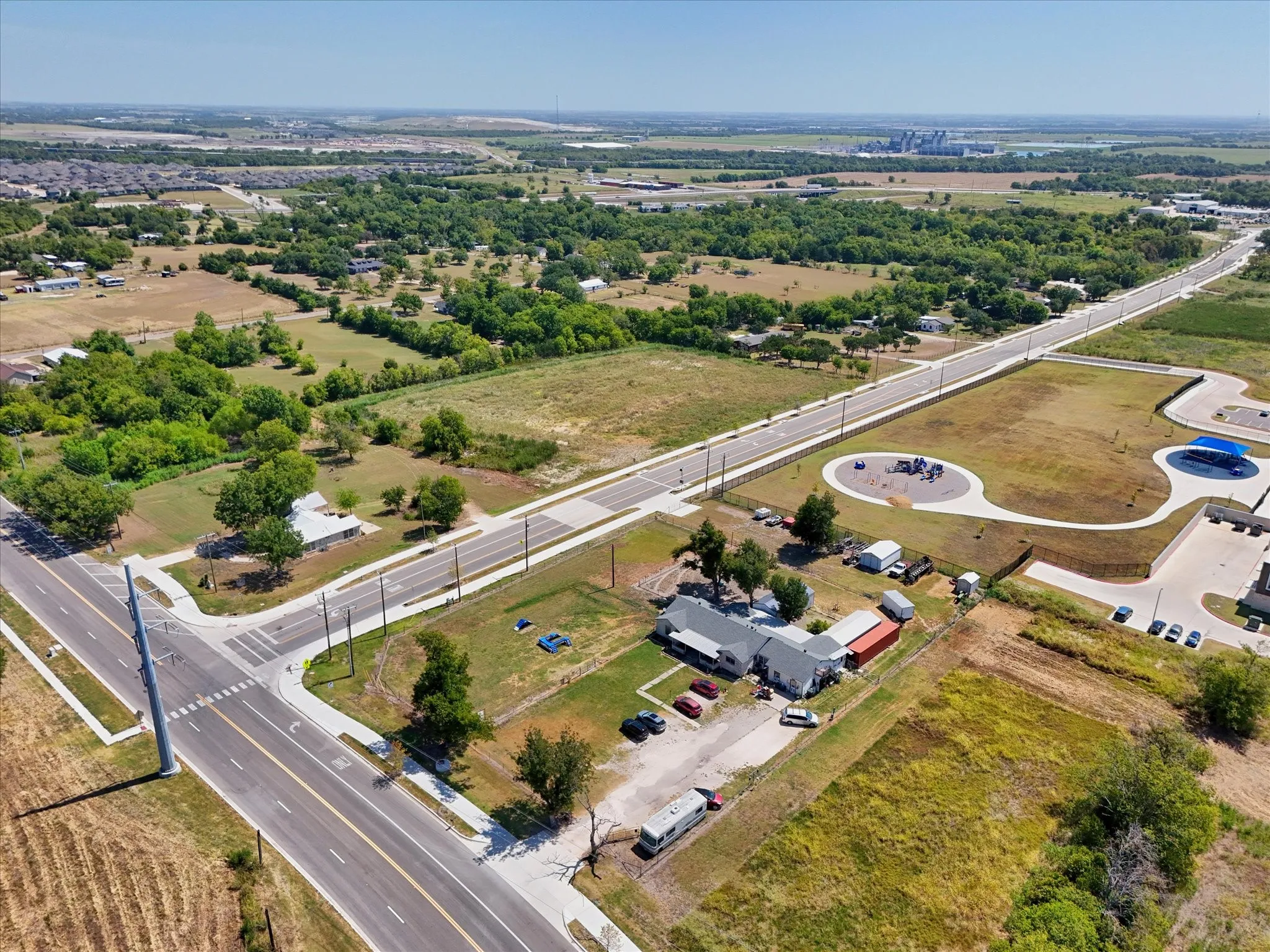 Expansive property featuring multiple structures, paved roads, and surrounding green spaces