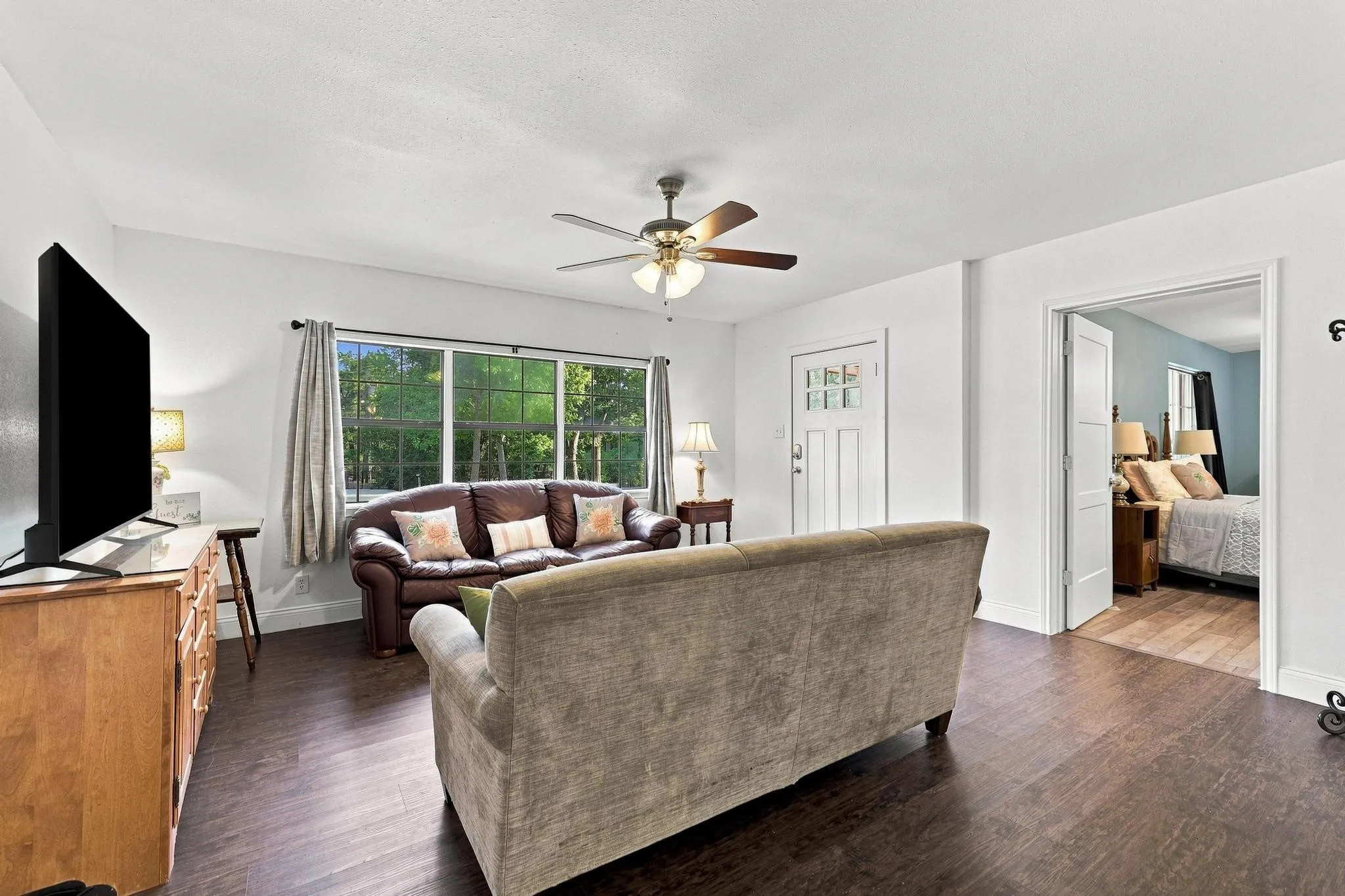 Wood-finish flooring throughout, with a ceiling fan, and white painted walls