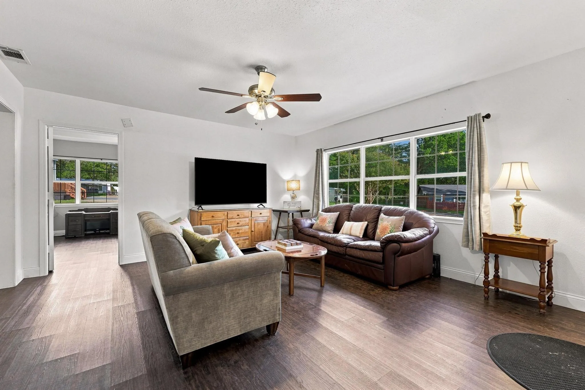 Spacious interior with dark wood-finish flooring, white walls, and a ceiling fan