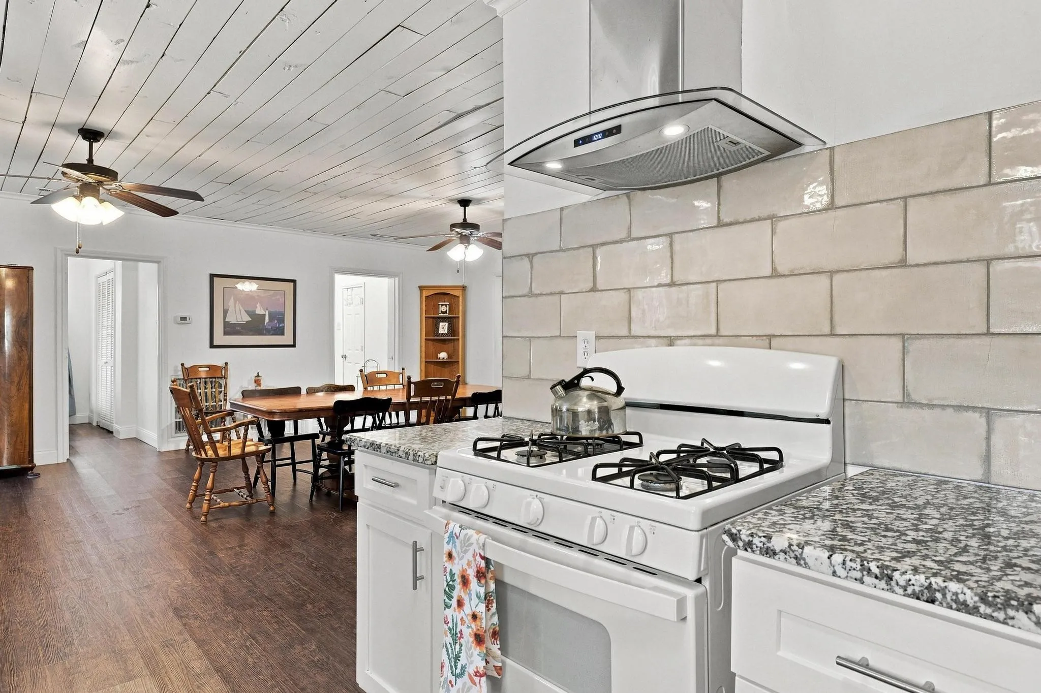 Kitchen featuring a white gas range, granite-finish countertops, and subway tile backsplash