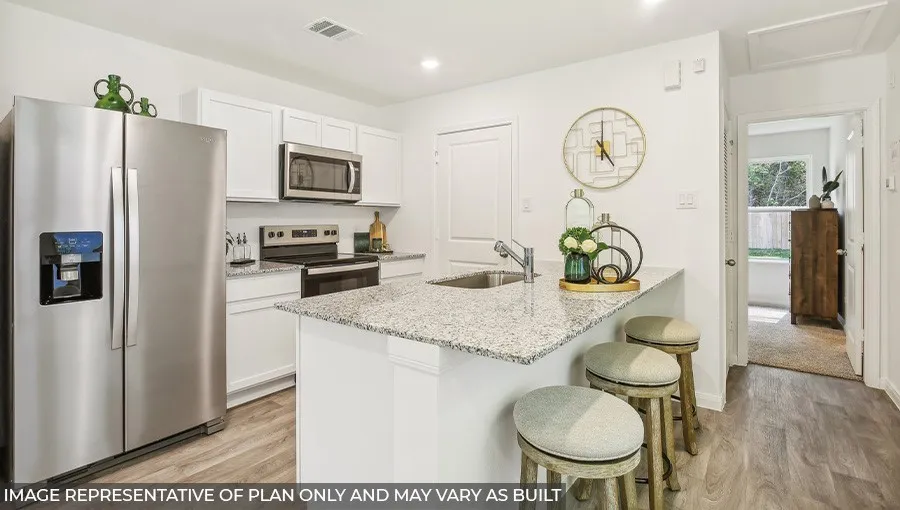 Modern kitchen featuring white cabinetry, stainless steel appliances including a refrigerator with ice and water dispenser, and a large granite-topped island with seating for two