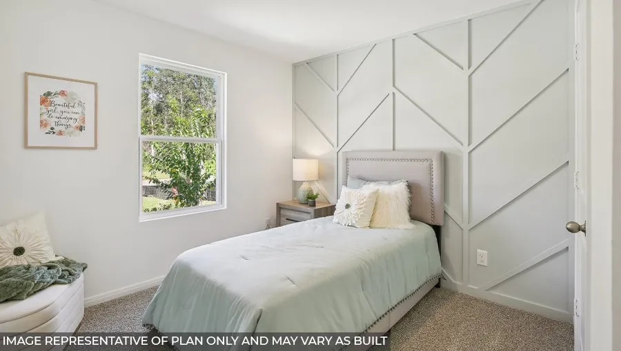 Bright secondary bedroom featuring a geometric accent wall with linear detailing, large operable window with natural light, neutral carpeting, and a coordinating upholstered headboard