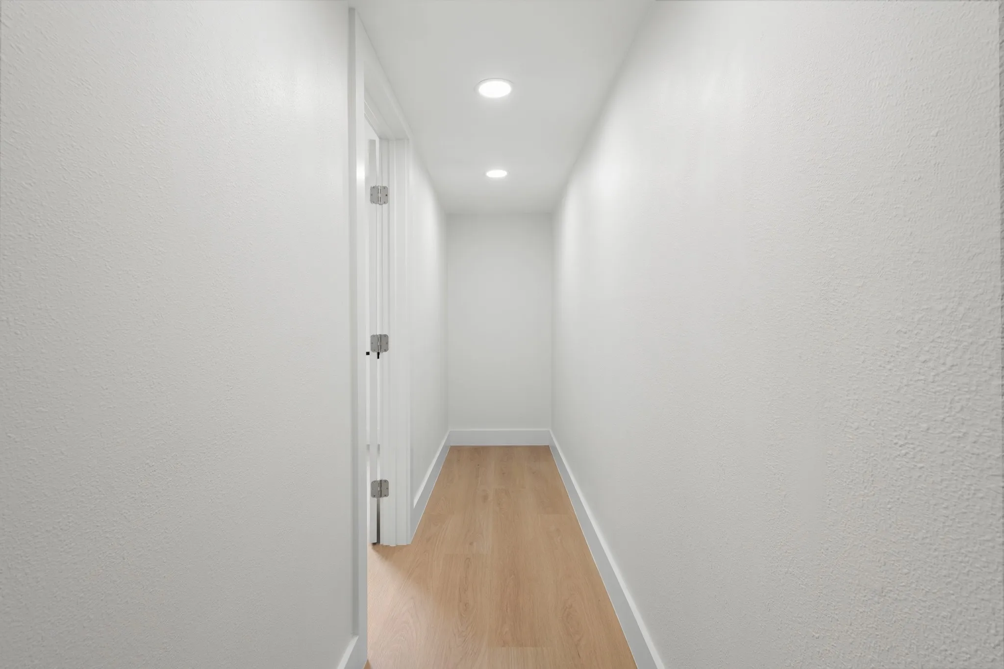 Recessed ceiling lighting, wood-finish flooring, white walls, white trim, and white doors