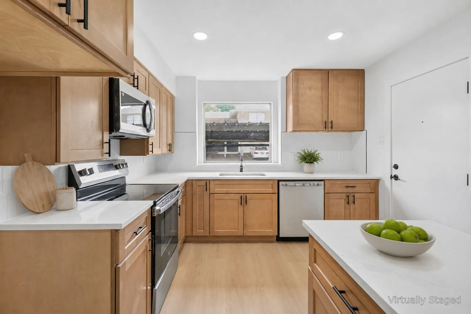 Kitchen featuring wood-finish cabinetry, white countertops, built-in stainless steel appliances, and a white subway tile backsplash