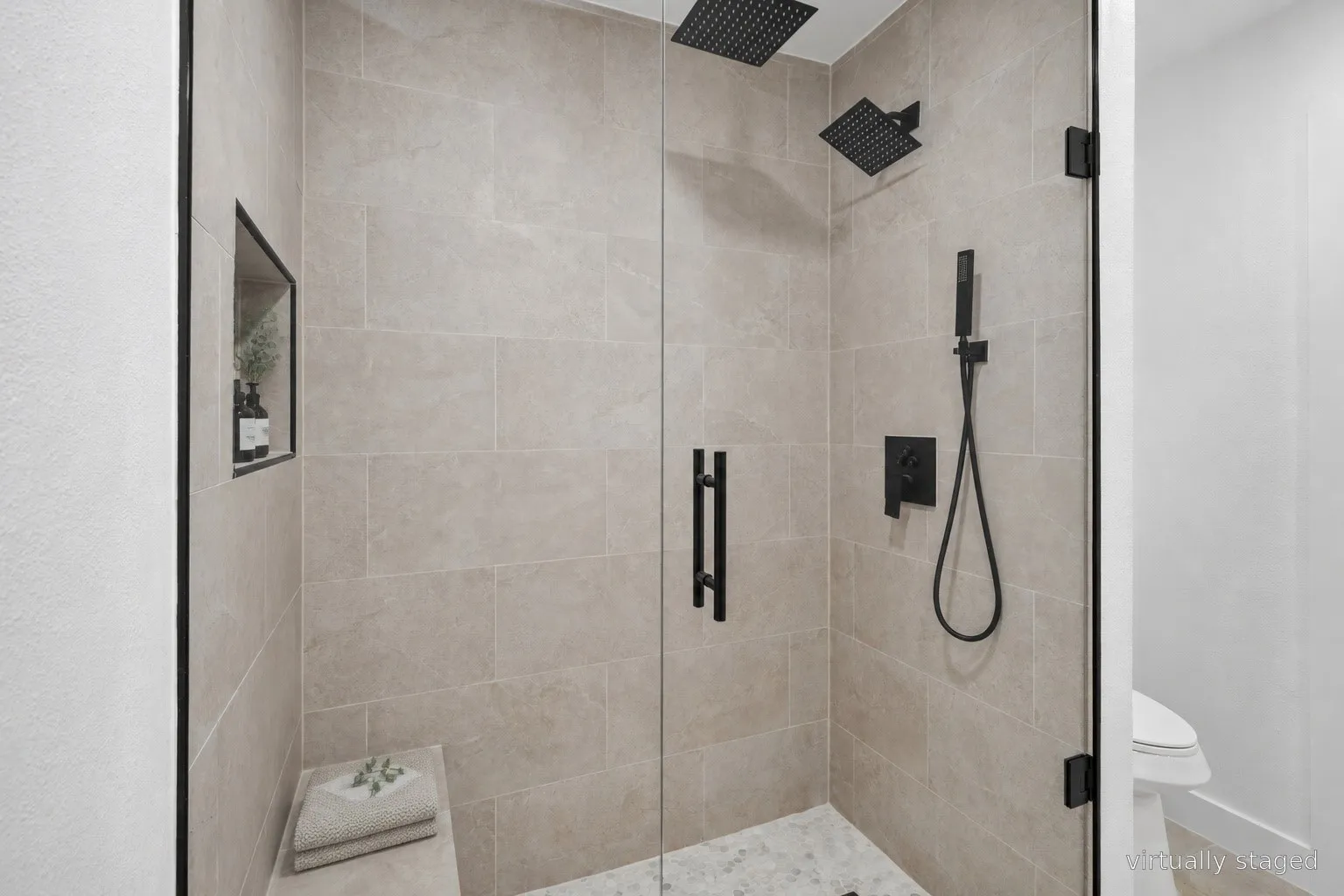 Glass-enclosed shower with a built-in bench and recessed niche