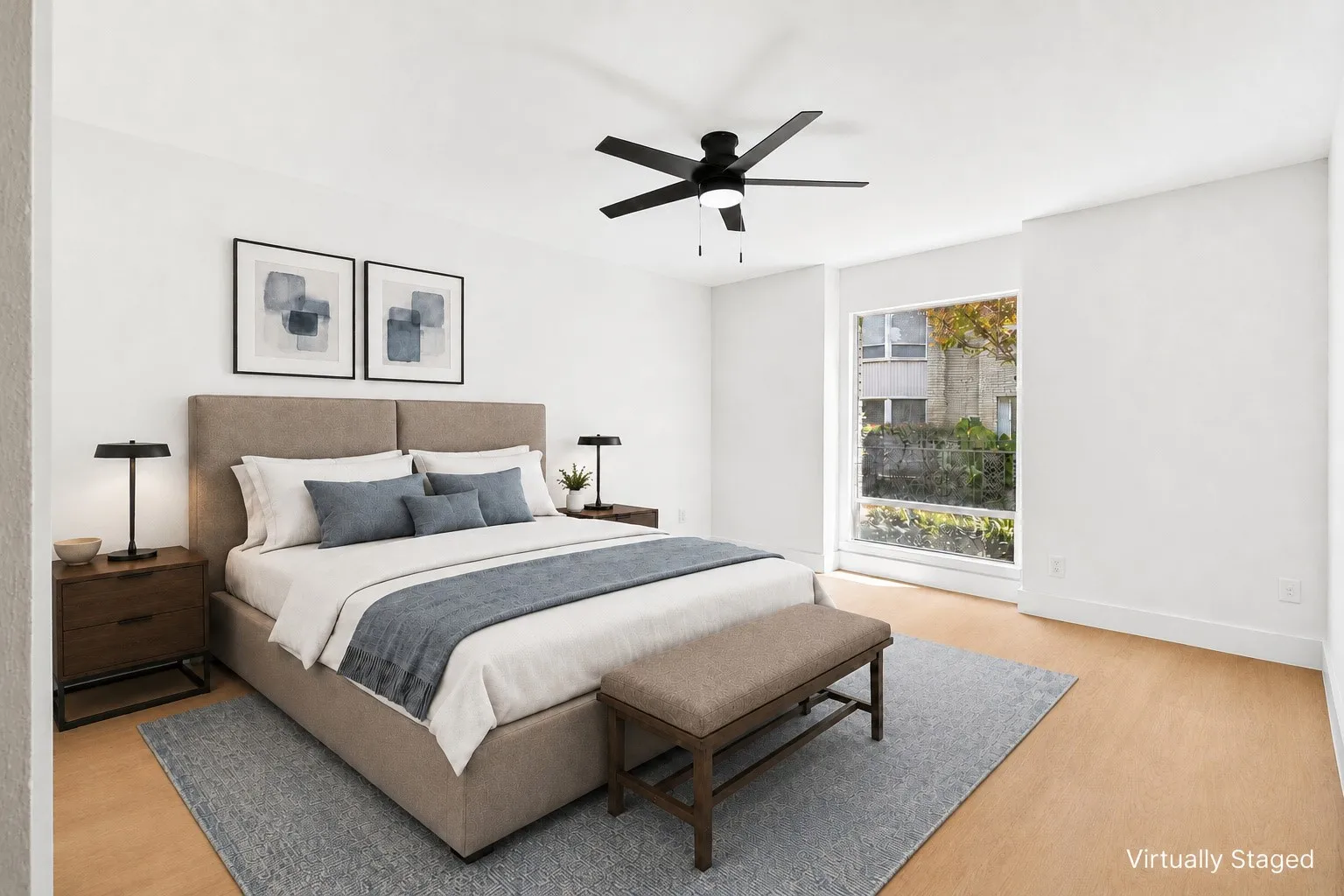 Light wood-finish flooring, white walls, large window with outdoor scenery, and a ceiling fan with integrated lighting