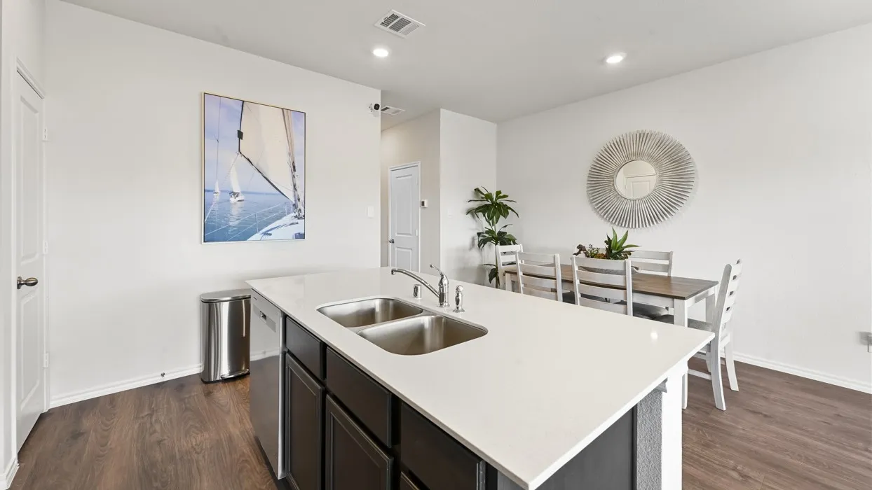 Kitchen island with dual stainless steel sinks, dark cabinetry, and a light-toned countertop