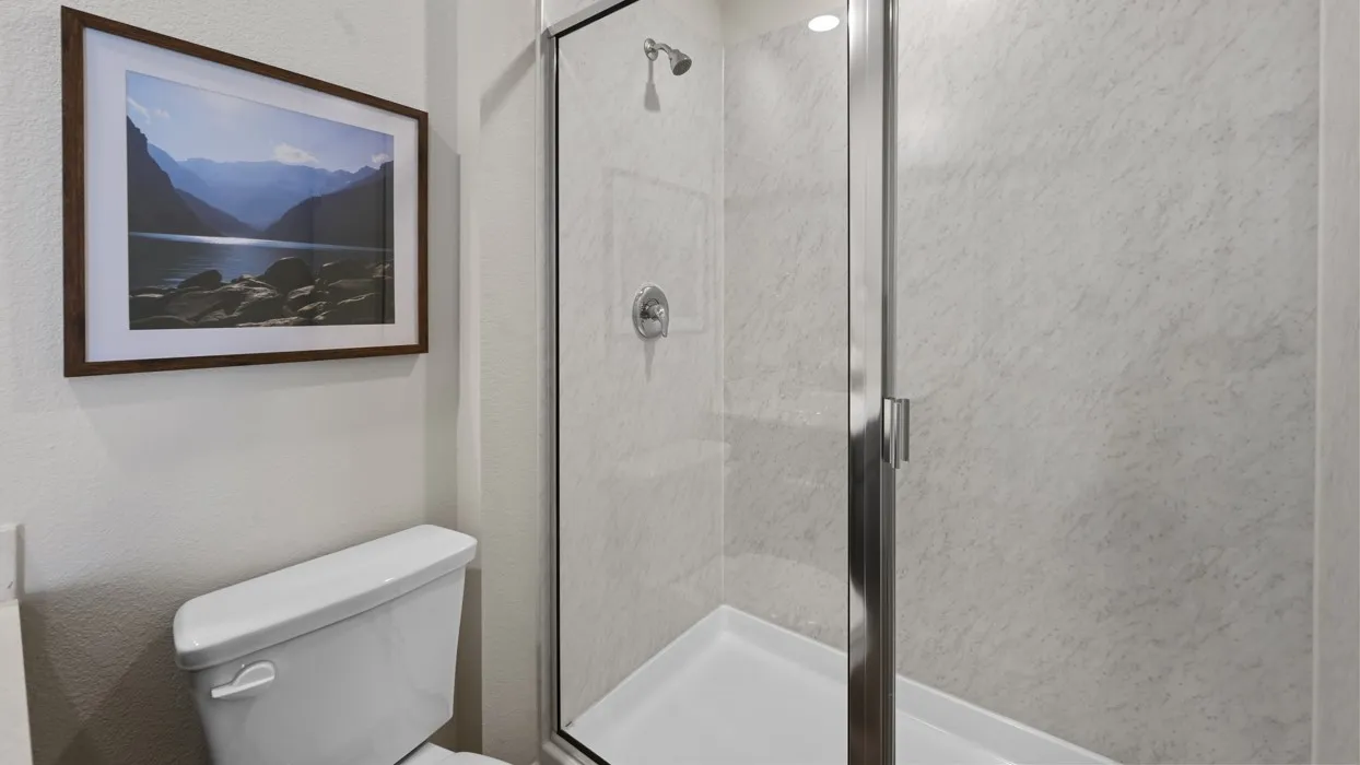 Glass-enclosed shower with a chrome shower head and shower control