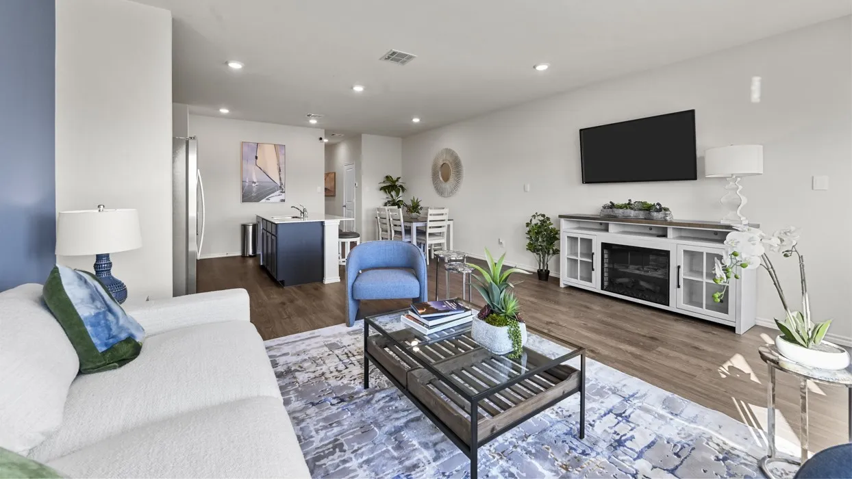 Open-concept living space featuring wood-finish flooring, recessed lighting, and a kitchen with an island and stainless steel refrigerator