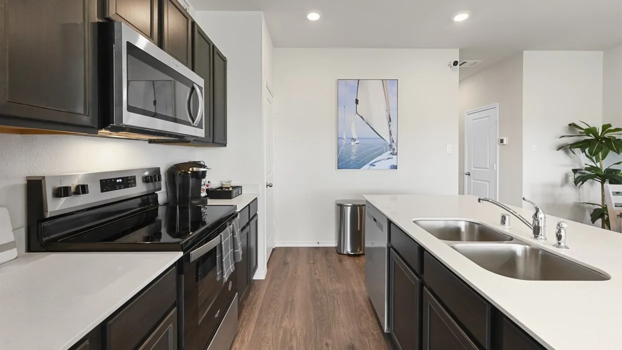 Modern kitchen featuring wood-finish flooring, dark cabinetry, and light-colored countertops