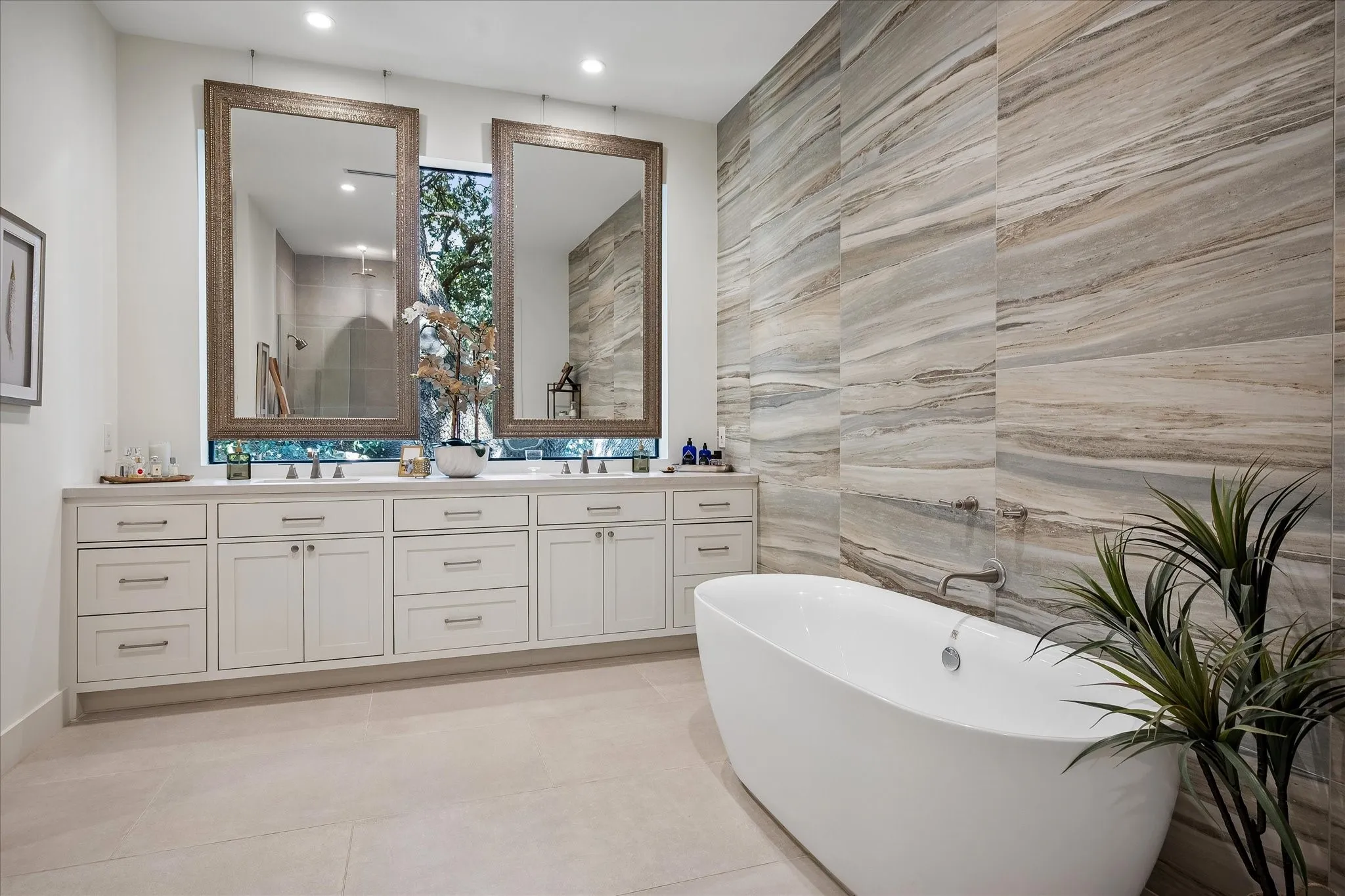 Primary spa-inspired bath invites nature in and boasts a wall of custom tile