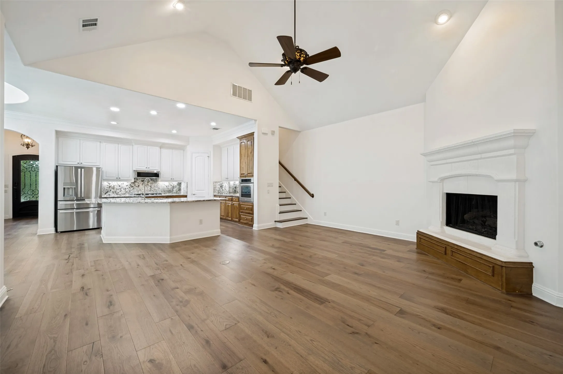 Designed for effortless entertaining, this open-concept living space seamlessly connects the family room and gourmet kitchen, featuring soaring vaulted ceilings, rich hardwood floors, a stunning cast stone fireplace, and an oversized island perfect for gathering with family and friends.