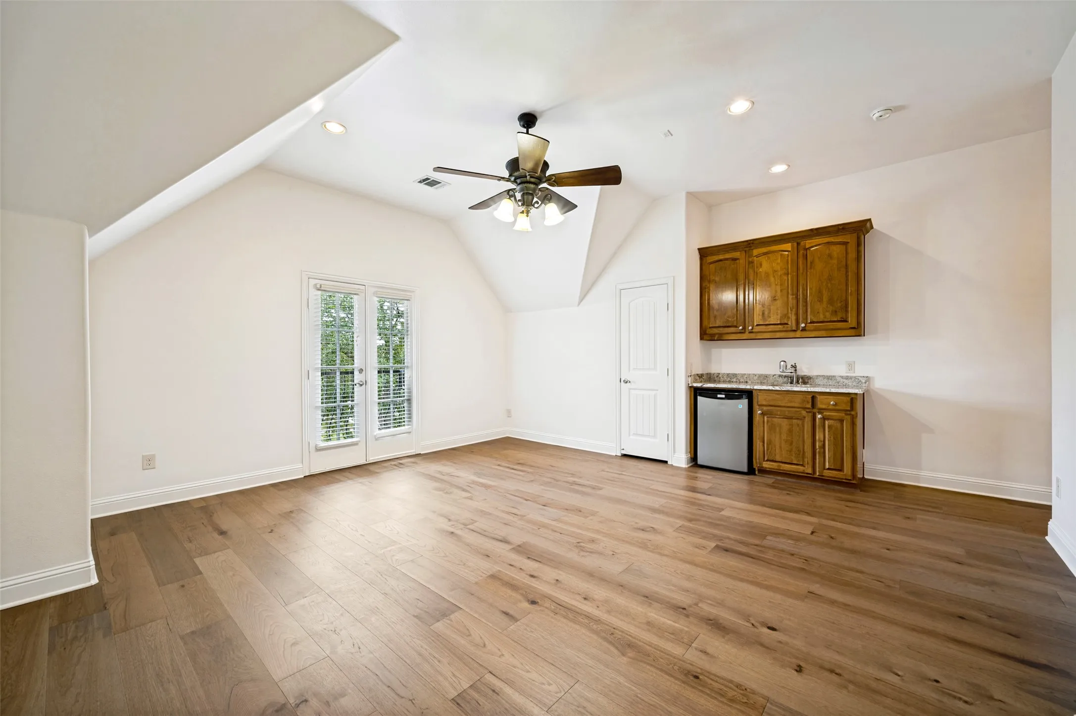 Designed for multigenerational living, this expansive upstairs suite includes a kitchenette, private bath, soaring ceilings, and ample space for both sleeping and living areas.