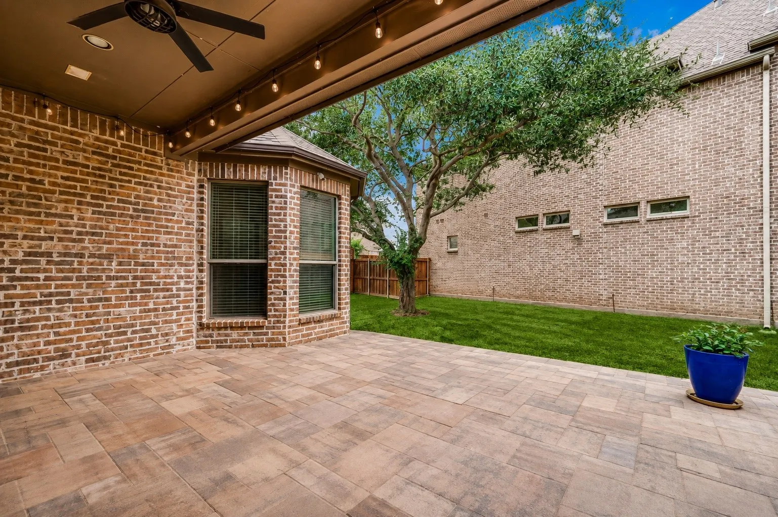 Enjoy year-round outdoor living on the expansive covered patio, complete with a ceiling fan, café string lighting, and ample space for dining and entertaining. The beautifully landscaped backyard offers lush green space and mature shade trees, creating a peaceful retreat for family and friends.