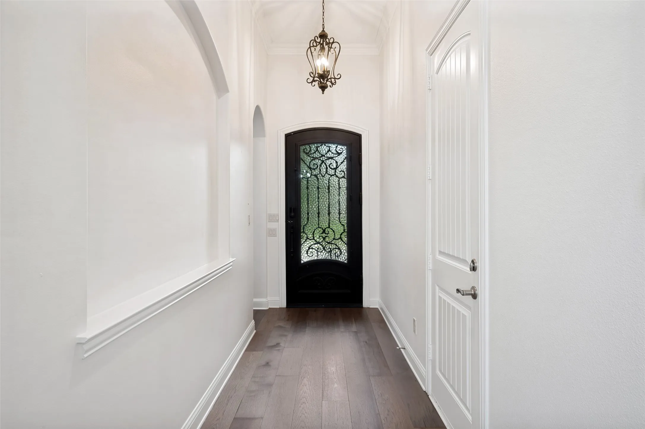 Step inside and be welcomed by soaring ceilings, elegant architectural details, a stunning wrought-iron front door, rich hardwood floors, and a dramatic designer chandelier that create a warm and inviting first impression.